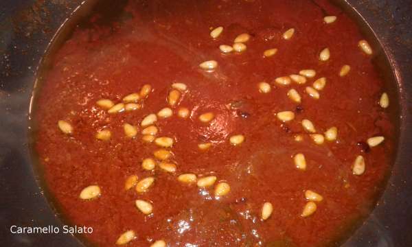 Aggiungere al condimento mettendo anche i pinoli e in ultimo il prezzemolo, aggiungere 3 cucchiai di acqua di cottura della pasta