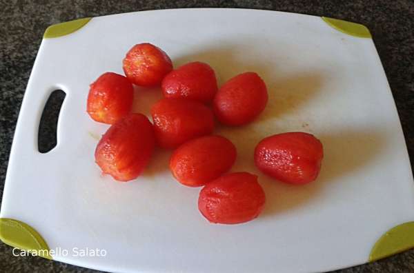 Scottare i pomodorini in acqua bollente e togliere la pellicola.
