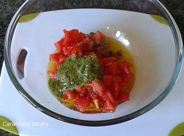 Porre i pomodori in una terrina, aggiungere il pesto e l'olio, salare e pepare.