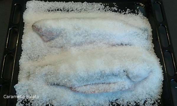 Versare 1 chilo di sale grosso nella teglia del forno, adagiare i pesci e ricoprirli con l'altro chilo di sale