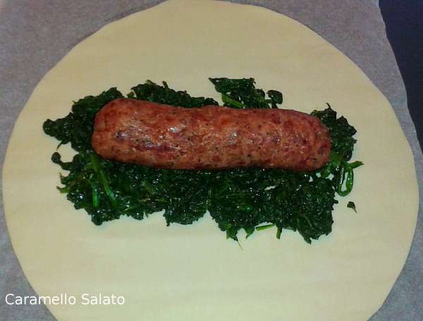 Una volta cotto il cotechino estrarre dalla stagnola, togliere la pelle. Aprire il rotolo di pasta sfoglia e disporvi un letto do spinaci ed il cotechino
