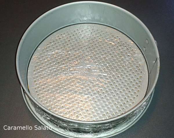 Foderare con pellicola uno stampo con cerchio apribile da 23 cm. e metterlo nel freezer